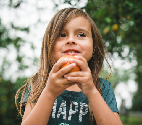 Child outside holding an apple in her hands